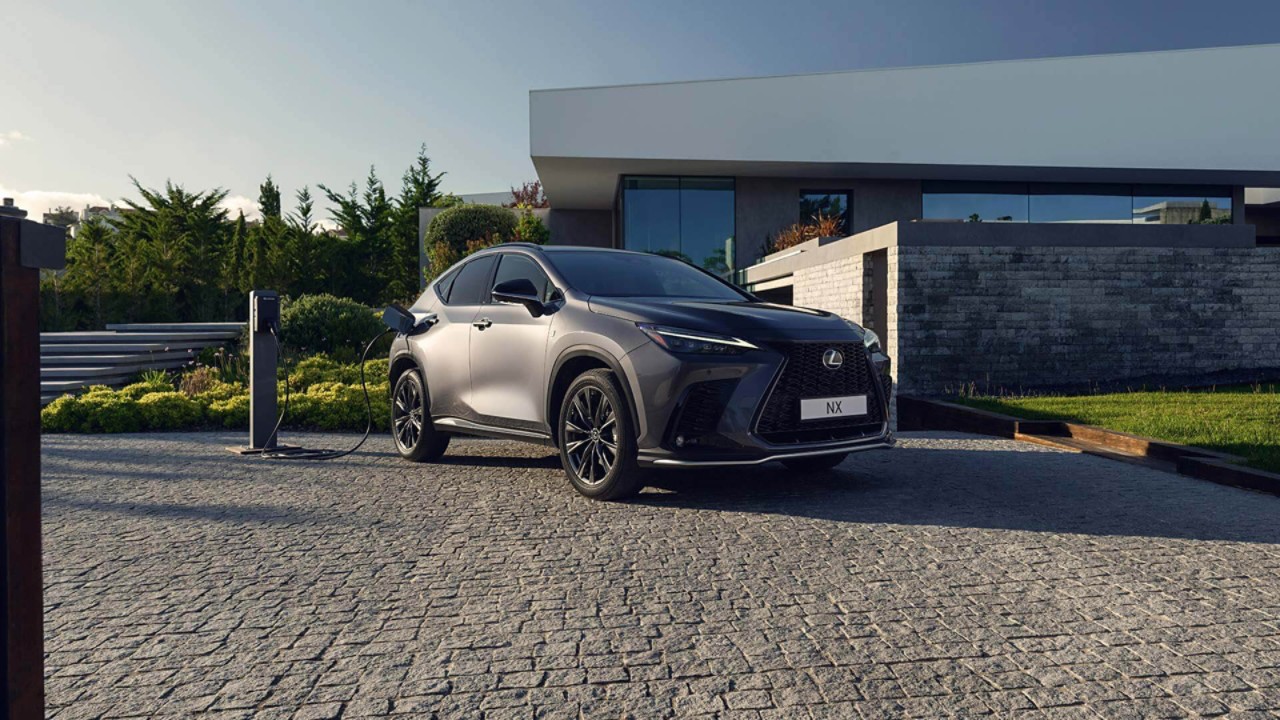 Ein Lexus NX, angeschlossen an eine Ladesäule vor einem Haus